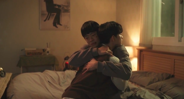 Our two leads share an intimate moment; hugging in a bedroom