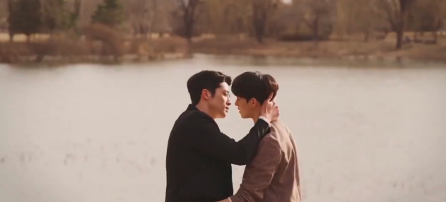 Our two leads are framed against a lake and are moving in for a kiss but their lips don't touch