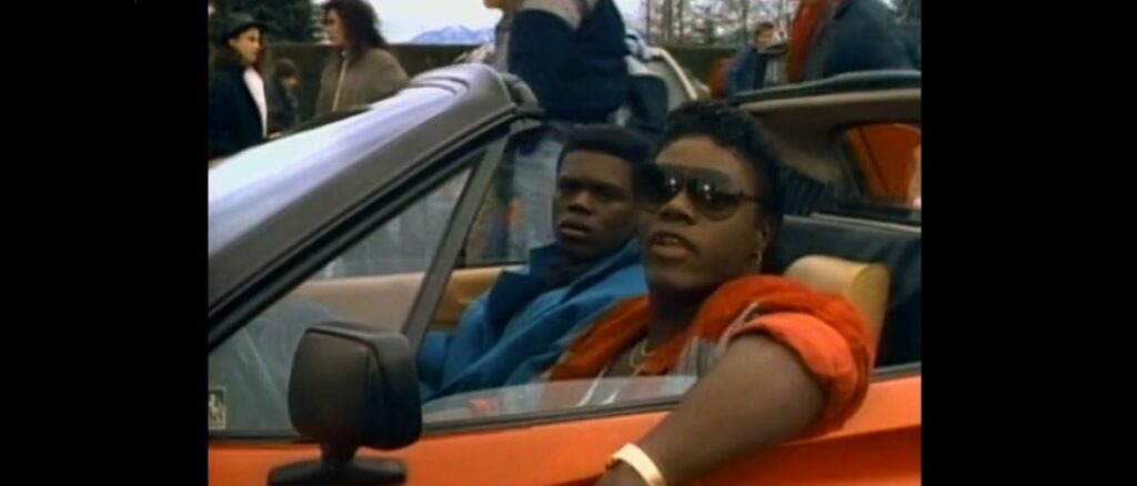 The thugs from the first scene show up to the school parking lot in a red Ferrari looking cool and dangerous