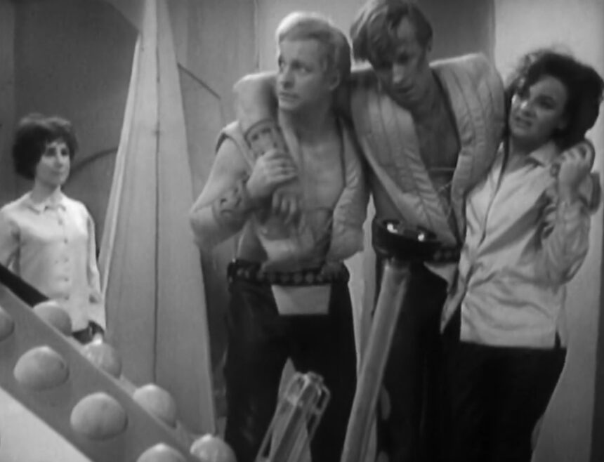 Barbara and some injured Thals look at the upturned dead Daleks with pain and concern on their faces as a stricken Susan looks on.