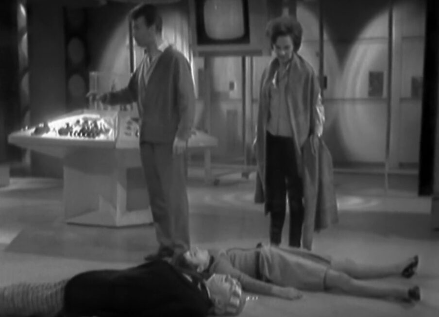 A confused Ian and Barbara look at the bodies of Susan and the Doctor lying unconscious on the floor