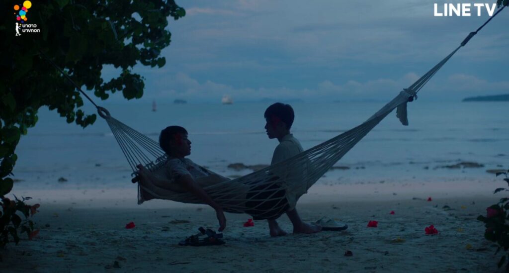 Two boys lie in a hammock as the sun rises across the turquoise sea before them.

One is all in; his legs tucked up besides the other boy's head, his hand gently on the other's knee. The lush long fingers of morning creep in towards them. The other boy's feet hang out the side of the hammock, touching the ground. Is he resting them or preparing to leave? Is he in or out of the hammock? It could be either.