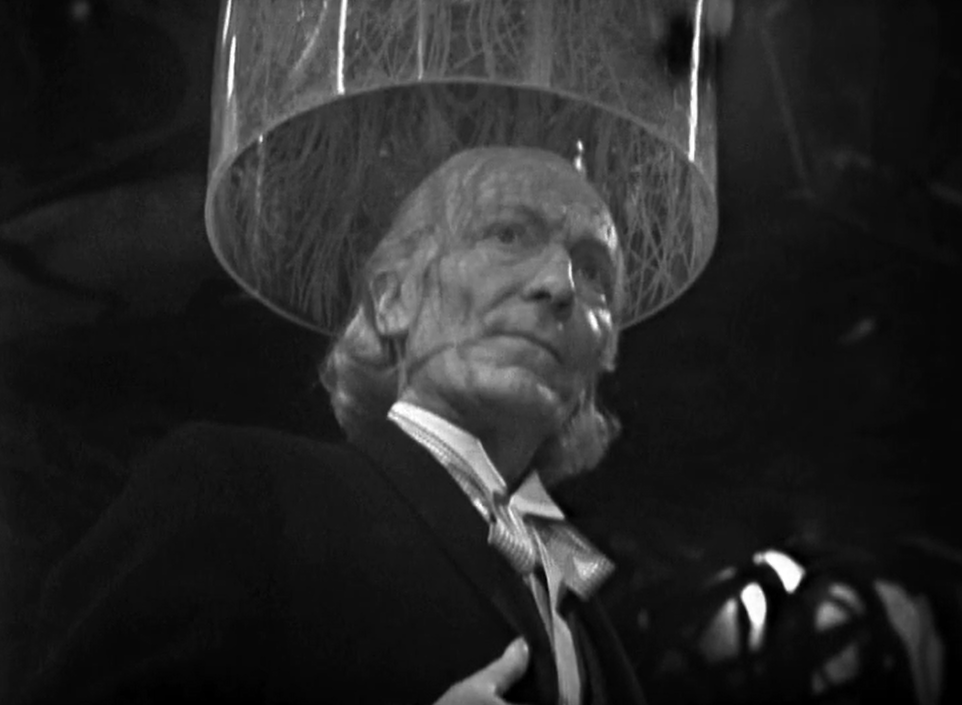 The Doctor stands beneath a cone of some kind 