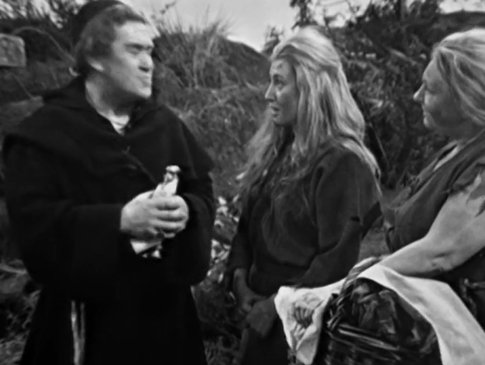 A man in monk's clothing - he's the Meddling Monk - talks to two local woman with long flowing hair and bare arms.