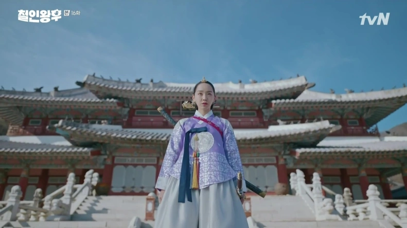 Shin Hye-sun stands looking regal in Hanbok with a Korean palace behind her